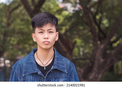 A Young Serious Lesbian Woman With Short Hair. Focusing Her Eyes To Each People In The Location. Feeling Bored, Annoyed And Tired Of Waiting. Standing Outside In The Park.