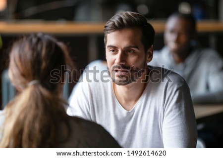 Young serious man having conversation with woman girlfriend sit at cafe table, focused male friend talking to female colleague client solving problem discuss work issues at meeting in coffeehouse