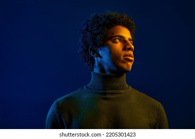 Young Serious Man Looking Away Over Dark Studio Background