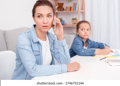 Young Serious Mom Sitting At Table Talking On Phone Solves Problems Running. Plays Baby Embarrassed. Sad Woman Sick Not Healthy Gets Bad News Frustrated. Horizontal Family Concept. Experiences, Worry