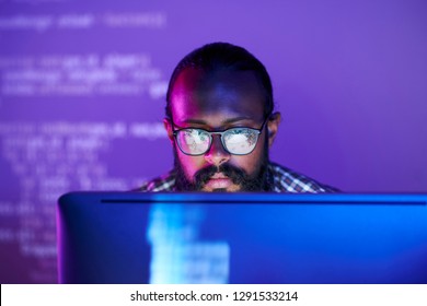 Young serious programmer in eyeglasses concentrating working and coded data computer screen