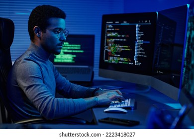 Young Serious Software Developer Typing On Desktop Keyboard While Working In Front Of Computer Monitors In Server Room