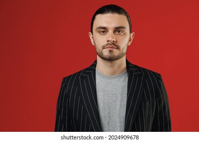 Young Serious Spanish Businessman Latin Man 20s With Long Hair Ponytail Wear Black Striped Jacket Grey Shirt Look Camera Isolated On Red Color Background Studio Portrait. Concept Of People Lifestyle