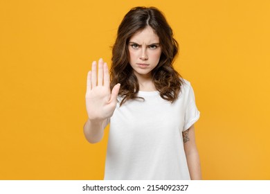 Young serious strict angry eueropean caucasian student woman 20s in white basic casual blank print design t-shirt show stop palm gesture refusing isolated on yellow orange background studio portrait - Powered by Shutterstock