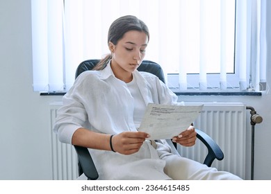 Young serious teenage student girl reading an important formal letter - Shutterstock ID 2364615485