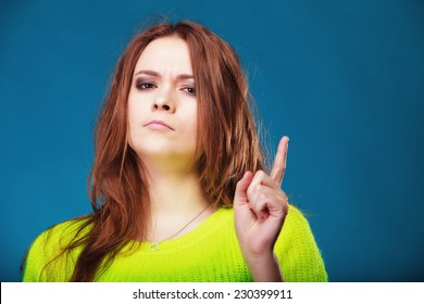 Young serious woman shaking wagging her finger teenage girl scolding on blue