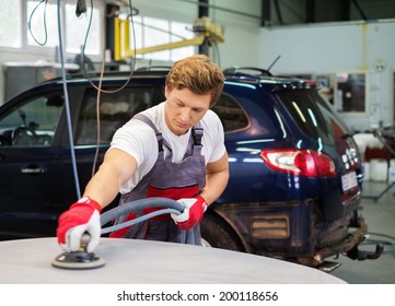 Young Serviceman Performing Grinding With Machine On A Car Bonnet In A Workshop