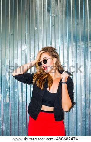 Young sexy bad girl on the background of metal walls, blonde wearing a black jacket