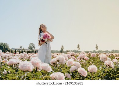 Young Sexy Beautiful Girl Collects Flowers On A Pink Peony Field. Woman On Vacation Roaming The Flower Garden. Leisure Concept. Basket With Flowers