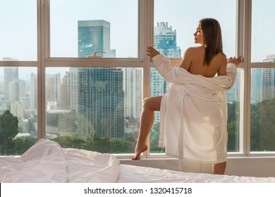 young sexy blonde standing topless near bedroom window dropping off her bathrobe