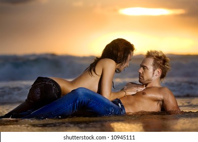 Young sexy couple on beach topless in jeans