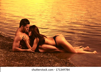 Young sexy couple on beach with sunset in background .Fashion colors. 