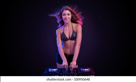 Young Sexy Deejay Woman Against Black Background With Strobe Light Effect. 