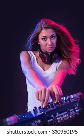 Young Sexy Deejay Woman Mixing Music Against Black Background With Strobe Light Effect. 