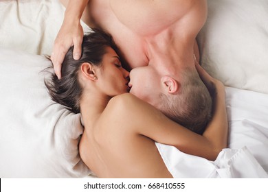 Young sexy heterosexual couple making love in bed. Young beautiful couple is lying on the bad face to face,close up. Top view. Couple in love. Hot guy. Fashion photo. Erotica concept. Love story.