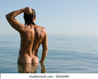 Young sexy muscular man standing in sea water in haze
