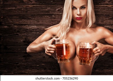 Young Sexy And Naked Oktoberfest Woman, Serving Big Beer Mugs On Wood Background.