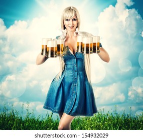 young sexy oktoberfest woman wearing a dirndl holding six beer mugs. outdoor background with grass and sky