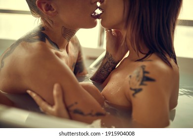 Ein junges, sexy, tätowiertes lesbisches Paar voller Leidenschaft hat Sex und genießt eine Badewanne in entspannter Atmosphäre im Badezimmer. Liebe, Beziehung, Bad, Schatz