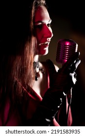 Young Sexy Woman Profile With A Beautiful Face And Lips, Red Dress, Immersed In A Studio Silver Microphone.