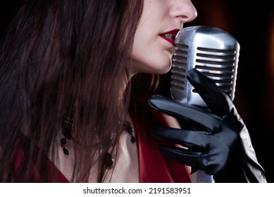 Young Sexy Woman Profile With A Beautiful Face And Lips, Red Dress, Immersed In A Studio Silver Microphone