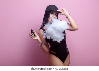 Young sexy woman is vaping. A cloud of vapor. Studio shooting.