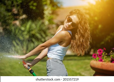 Young Sexy Woman Is Watering A Garden.