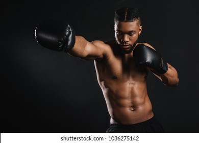 young shirtless african american sportsman in boxing gloves training isolated on black - Powered by Shutterstock