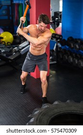 Young Shirtless Man Doing Sledgehammer Swing Exercise In Gym