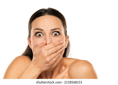 Young shirtless shocked woman covers her mout with the hand on a white background