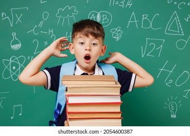 Young shocked male kid school boy 5-6 years old wearing t-shirt backpack look at books isolated on green wall chalk blackboard background studio. Childhood children kids education lifestyle concept - Powered by Shutterstock