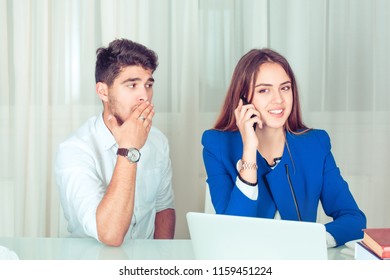 Young Shocked Man Covering Mouth While Eavesdropping Secretly Listening Juicy Gossip Conversation Of Young Woman Having Smartphone Call While Sitting Near At Table In The Office At Workplace Or Home