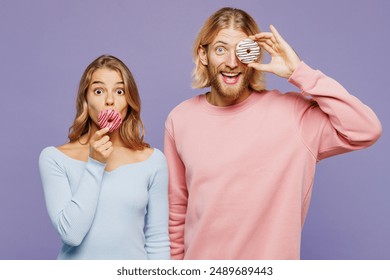 Young shocked surprised excited fun happy couple two friends family man woman wear pink blue casual clothes together hold in hand cover eye with donut isolated on pastel plain light purple background - Powered by Shutterstock