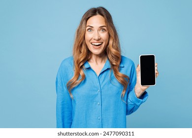 Young shocked surprised woman wears shirt casual clothes hold in hand use mobile cell phone with blank screen workspace area isolated on plain pastel light blue background studio. Lifestyle concept - Powered by Shutterstock