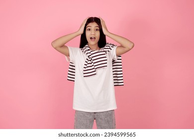 Young shocked teenage girl on pink background in studio. - Shutterstock ID 2394599565