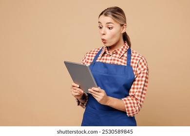 Young shocked woman barista bartender barman employee wears blue apron red shirt work in coffee shop use digital tablet pc computer isolated on plain beige background. Small business startup concept - Powered by Shutterstock