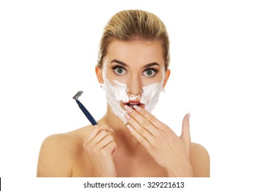 Young shocked woman shaving her face with a razor, isolated on white