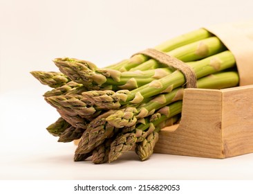 Young shoots of chocolate asparagus in a wooden box. The shoots are wrapped in craft paper and tied with natural thread.