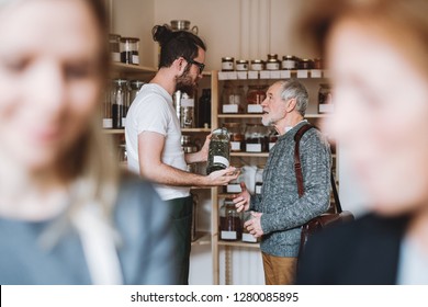 Young Shop Assistant Serving A Senior Man In A Zero Waste Shop.