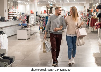 Young Shoppers With Paperbags Leaving Casualwear Department After Buying New Clothes To Go On Shopping In The Mall