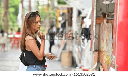 Young shopping woman waiting and looking on food truck in park, Food street concept.