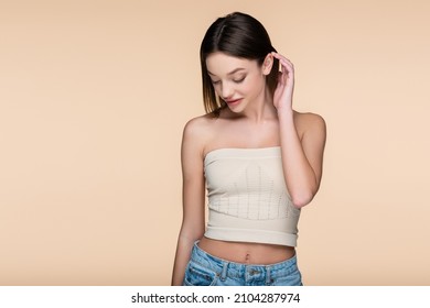 Young And Shy Woman In Crop Top With Bare Shoulders Isolated On Beige