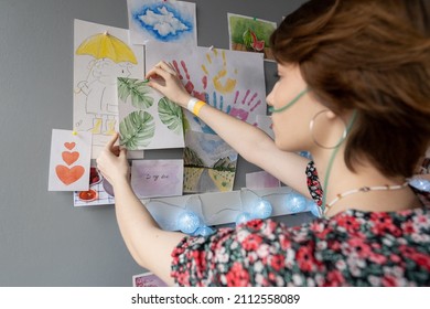 Young sick female patient and oxygen nose pipe putting her friends drawings wall hospital ward