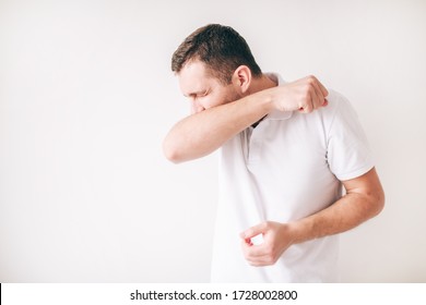 Young Sick Man Isolated Over White Background. Cough Out Loud And Cover Mouth With Elbow. Painful Coughing. Guy In Studio Stand Alone. Suffer From Sickness.