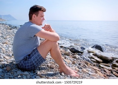 Young Sick Man Uses Nebulizer Sits On Seaside. Inhaling Inhaler Mask. Fibrosis Cystic Copd And Treatment Inhaler. Asthma Pulmonary Respiratory Breath Problem And Cure. Painkiller Sedative Gas Oxygen.