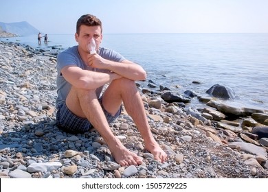 Young Sick Man Uses Nebulizer Sits On Seaside. Inhaling Inhaler Mask. Fibrosis Cystic Copd And Treatment Inhaler. Asthma Pulmonary Respiratory Breath Problem And Cure. Painkiller Sedative Gas Oxygen.