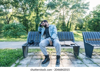 Young Sick Mentally Ill Tired Poor Dirty Drunk Alcoholic Homeless Man Or Refugee Sleeping On The Wooden Bench On The Urban Street In The City, Homelessness Social Documentary Concept