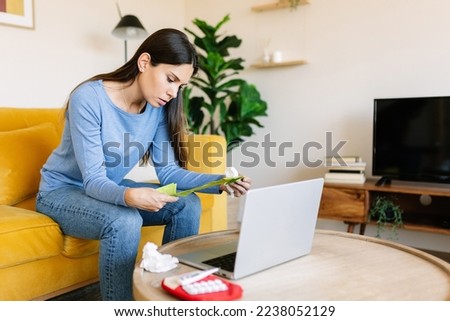 Young sick woman reading medication instructions while sitting on sofa at home. Telemedicine and medical lifestyle concept