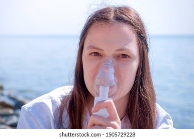 Young Sick Woman Use Nebulizer On Seaside. Inhaling Inhaler Mask. Fibrosis Cystic Copd And Treatment Inhaler. Asthma Pulmonary Respiratory Breath Problem And Cure. Painkiller Sedative Gas Oxygen.