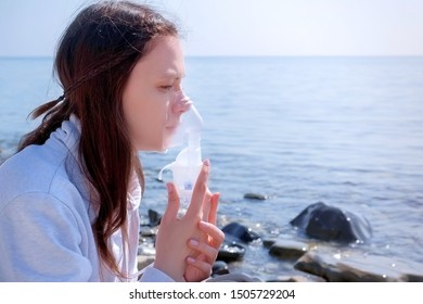 Young Sick Woman Uses Nebulizer On Seaside. Inhaling Inhaler Mask. Fibrosis Cystic Copd And Treatment Inhaler. Asthma Pulmonary Respiratory Breath Problem And Cure. Painkiller Sedative Gas Oxygen.